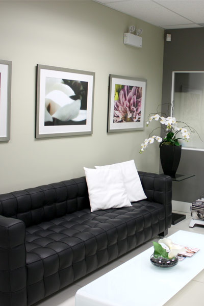 The waiting room for our massage spa in Surrey showing a couch with pillows, and a table.